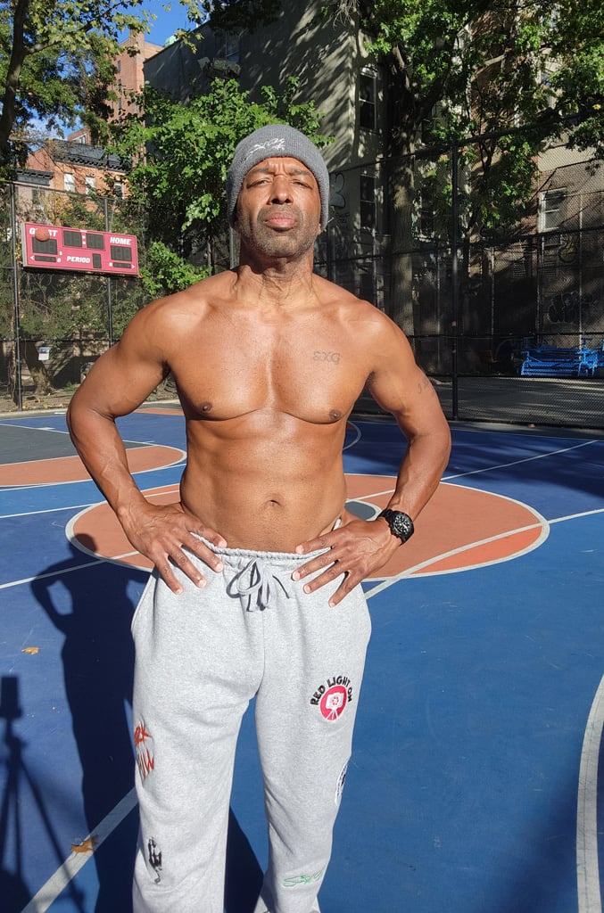 Coach is posing outdoors showing his abs.